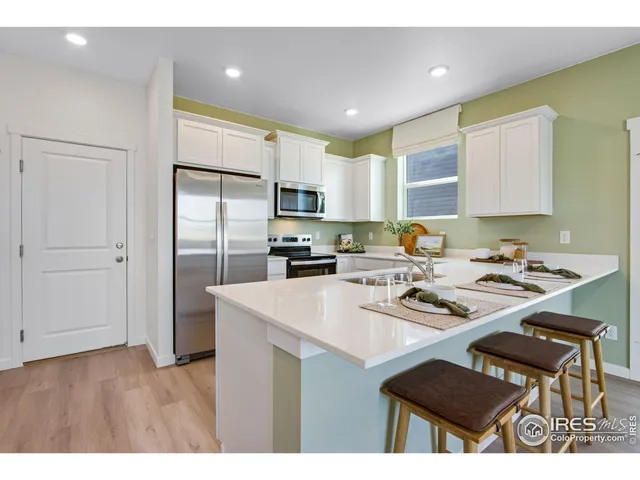 a kitchen with a refrigerator a stove a sink dishwasher with a dining table and chairs