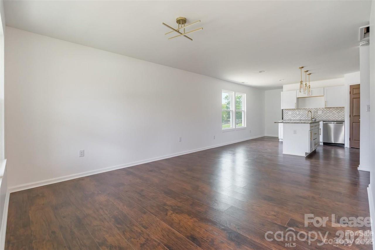 303 Cabarrus Avenue West Concord, NC 28025 - Photo 2 of 17 a view of empty room with wooden floor and kitchen view