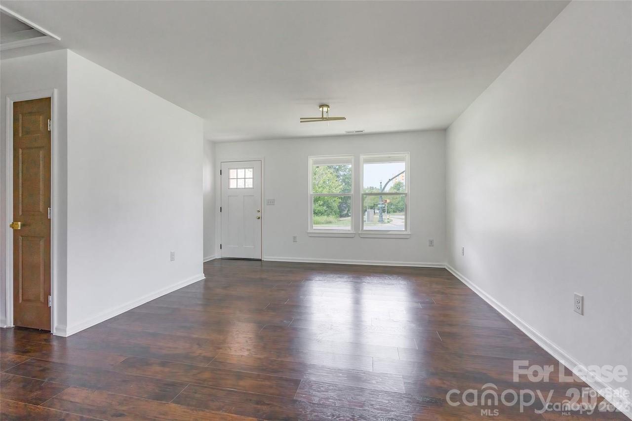 303 Cabarrus Avenue West Concord, NC 28025 - Photo 3 of 17 an empty room with wooden floor and windows