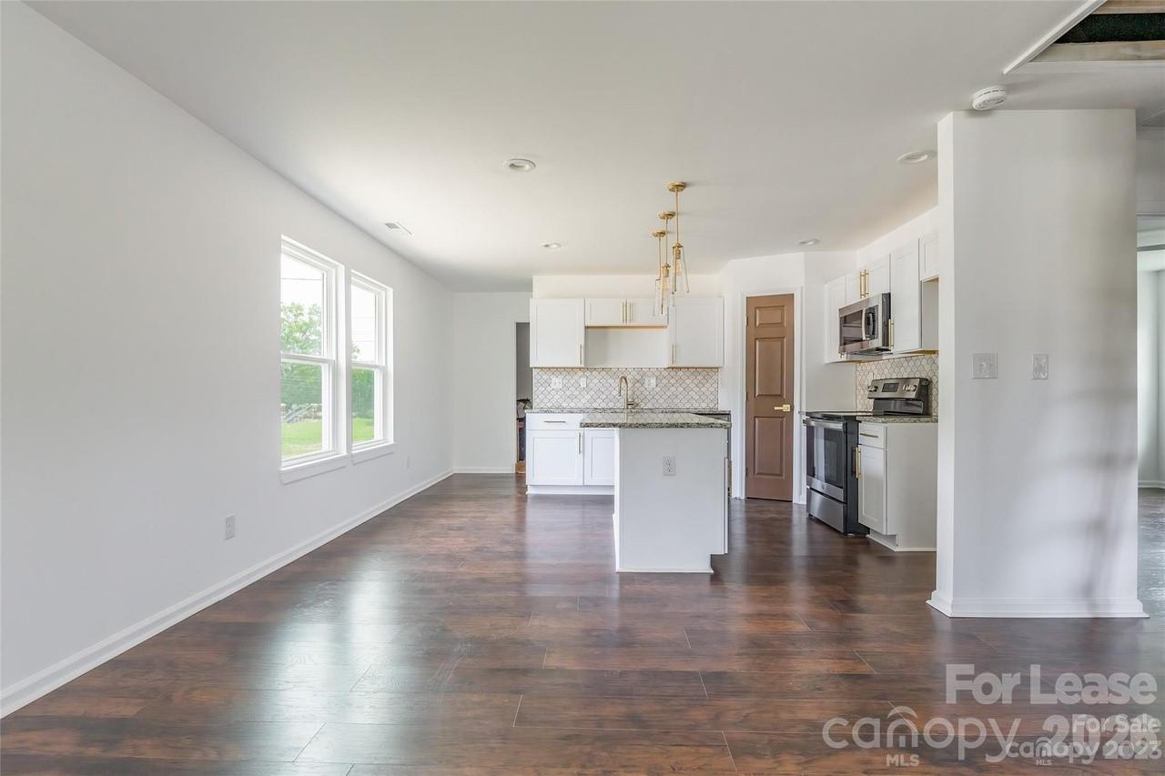 303 Cabarrus Avenue West Concord, NC 28025 - Photo 4 of 17 a kitchen with stainless steel appliances kitchen island granite countertop a refrigerator a sink a stove and white cabinets with wooden floor