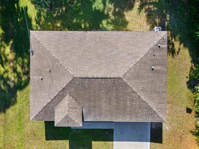 an aerial view of a house with a yard and large tree