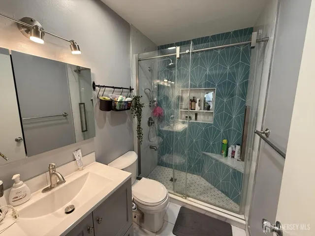 a bathroom with a shower sink vanity mirror and toilet