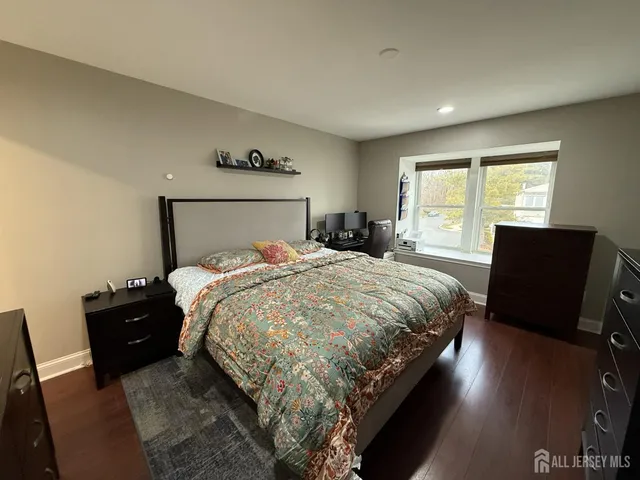 a bed sitting in a spacious bedroom next to a window and wooden floor