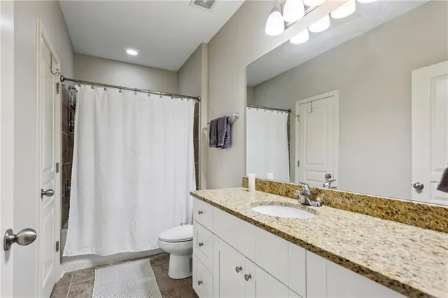 a bathroom with a granite countertop sink toilet and shower