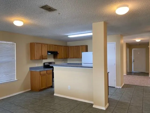 a kitchen with stainless steel appliances a sink a stove a refrigerator cabinets and a window