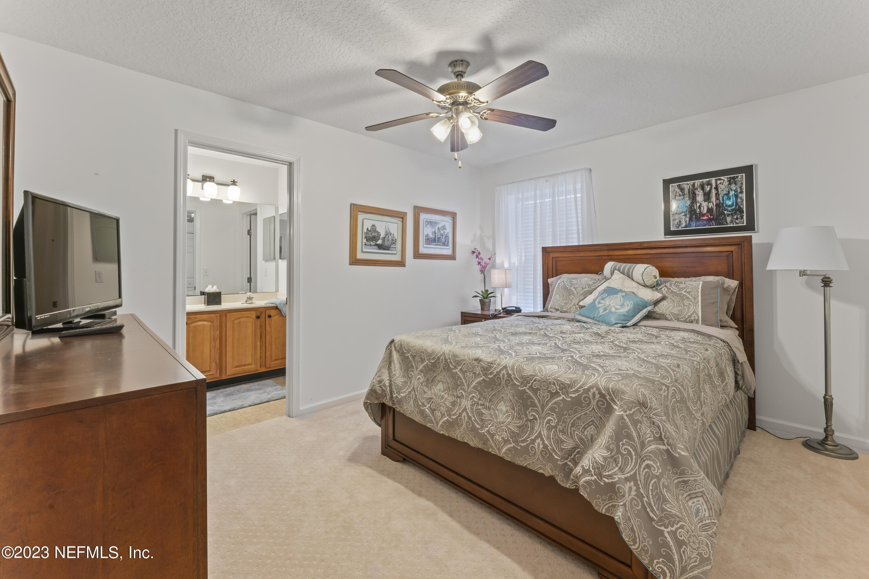 1840 Copper Stone Drive, Unit D Fleming Island, FL 32003 - Photo 26 of 66 a bedroom with a large bed and a flat tv screen on dresser