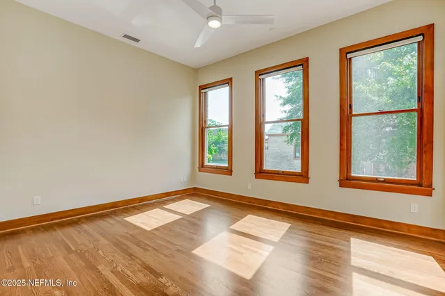 a view of an empty room with a window and wooden floor