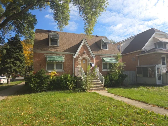 a view of a brick house with a big yard plants and large trees