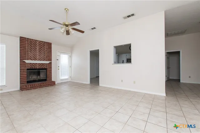 an empty room with windows and fireplace