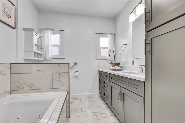 a bathroom with a granite countertop sink a mirror and a bathtub