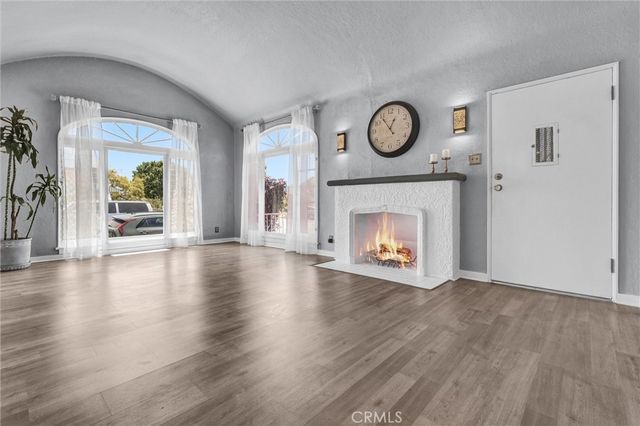 a view of an empty room with wooden floor fireplace and a window