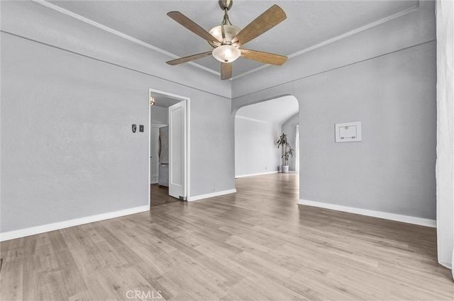 an empty room with wooden floor and ceiling fan