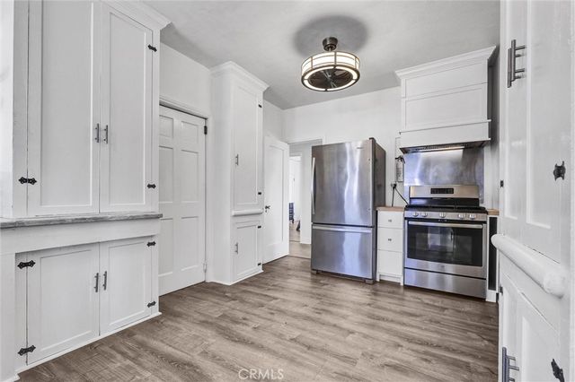 a kitchen with stainless steel appliances a refrigerator a stove a sink and white cabinets