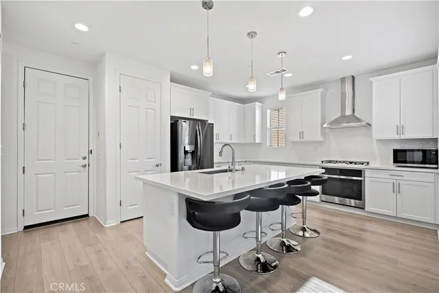 a kitchen with stainless steel appliances kitchen island a table chairs refrigerator and microwave