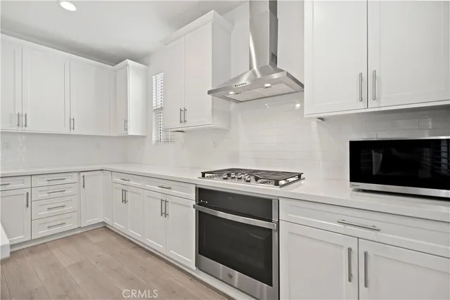 a kitchen with white cabinets stainless steel appliances and wooden floor
