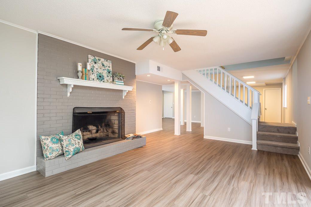 8913 Hunting Trail Raleigh, NC 27613 - Photo 12 of 19 a view of a livingroom with wooden floor a fireplace and a ceiling fan