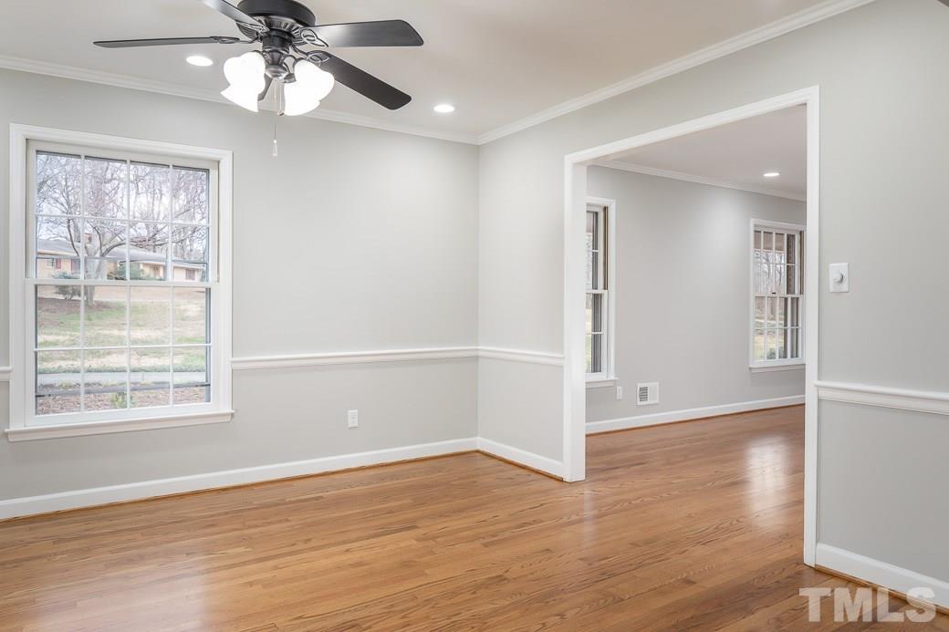 8913 Hunting Trail Raleigh, NC 27613 - Photo 4 of 19 an empty room with wooden floor chandelier fan and windows