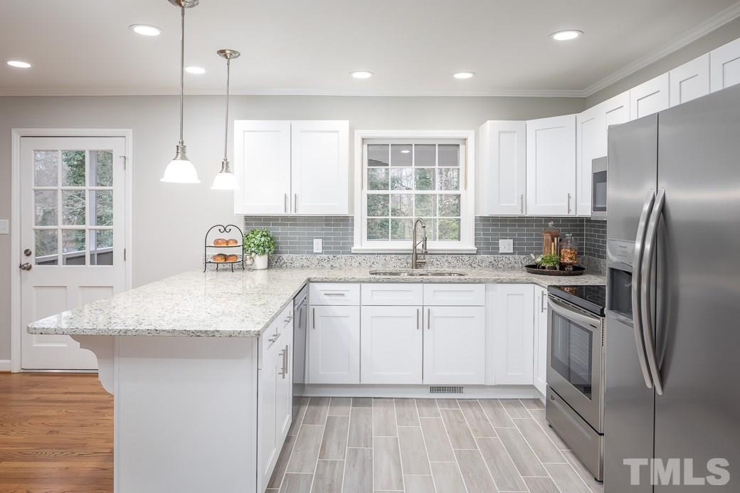 8913 Hunting Trail Raleigh, NC 27613 - Photo 5 of 19 a kitchen with kitchen island granite countertop a sink stove and refrigerator