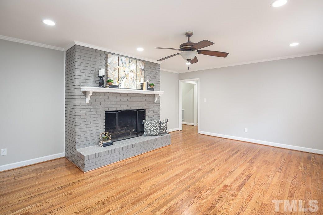 8913 Hunting Trail Raleigh, NC 27613 - Photo 7 of 19 a view of a livingroom with a fireplace a ceiling fan and wooden floor