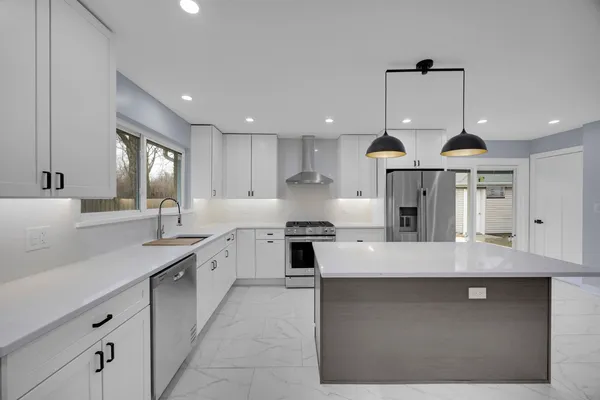 a large kitchen with stainless steel appliances kitchen island granite countertop a sink a stove and a window
