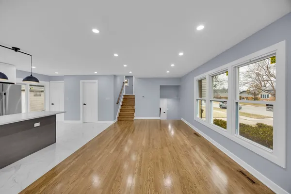 a view of an empty room with wooden floor and windows