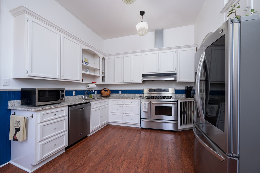 215 7th Street Columbus, GA 31901 - Photo 24 of 64 a kitchen with granite countertop a refrigerator stove and white cabinets