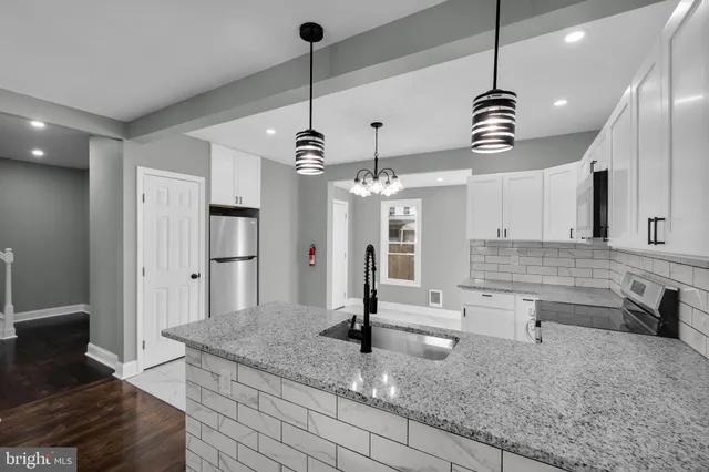 a view of a kitchen with granite countertop stainless steel appliances and a chandelier