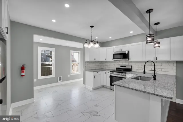 a kitchen with stainless steel appliances granite countertop a sink dishwasher a stove and a refrigerator with wooden floor