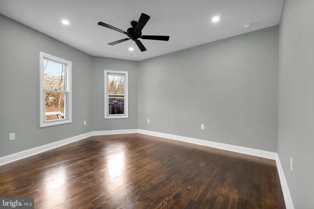 a view of empty room with wooden floor and ceiling fan