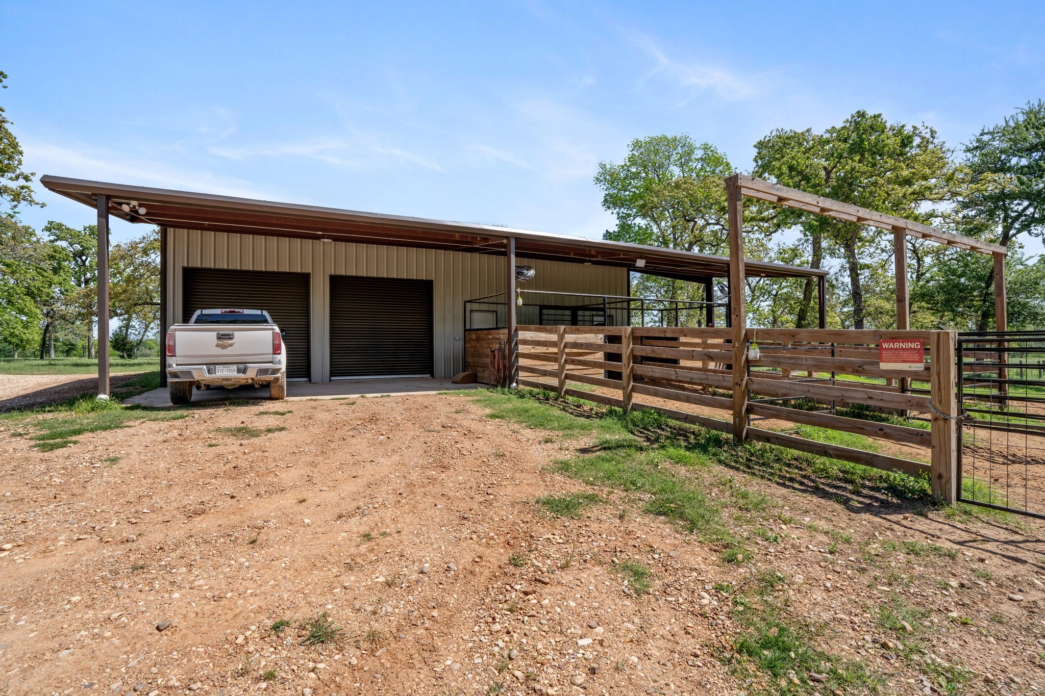 4052 Kuykendall Road Bellville, TX 77418 - Photo 29 of 40 The barn has two large roll-up doors and an attached fenced area, ideal for livestock or storage. Surrounded by trees.