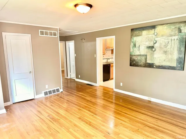 a view of an empty room with wooden floor and a window