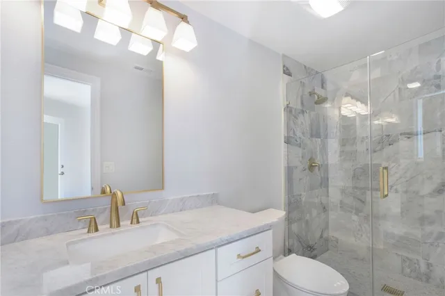 a bathroom with a granite countertop sink toilet a mirror a vanity and shower