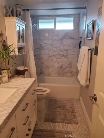 a bathroom with a granite countertop sink a toilet and shower