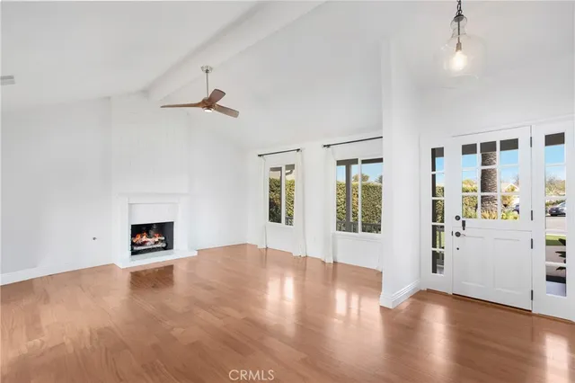 an empty room with wooden floor fireplace and windows