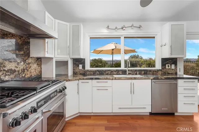 a kitchen with stainless steel appliances granite countertop a stove and a white cabinets