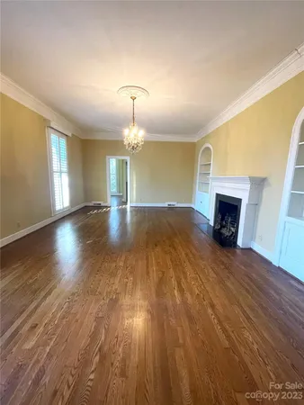 an empty room with wooden floor fireplace and window