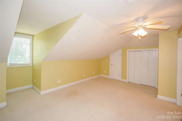 an empty room with a ceiling fan and carpet
