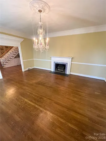a view of a room with wooden floor chandelier and fireplace