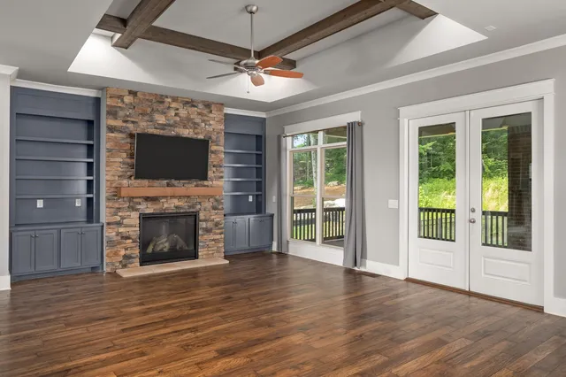 a view of an empty room with wooden floor fireplace and a window