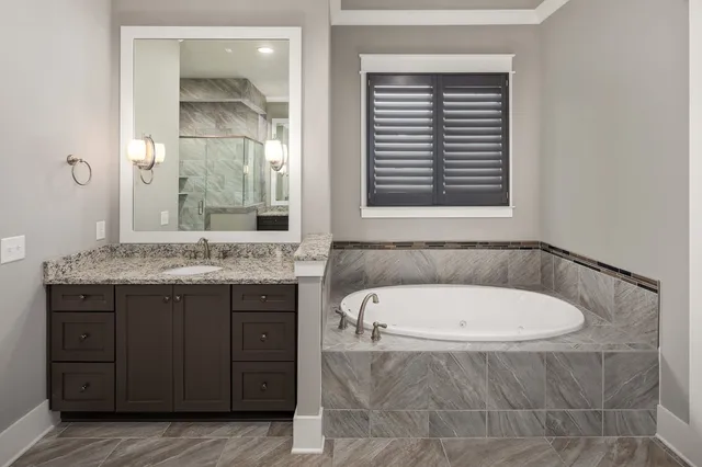 a bathroom with a tub a sink and a large mirror