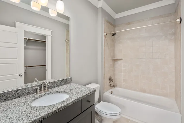 a bathroom with a granite countertop bathtub shower sink vanity mirror and toilet