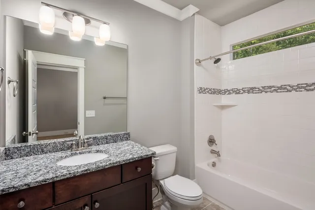 a bathroom with a granite countertop sink mirror vanity and toilet