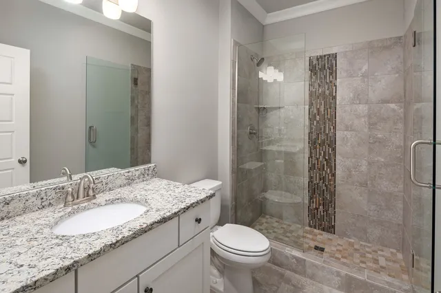 a bathroom with a granite countertop sink toilet mirror and shower
