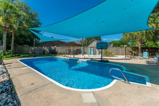 a view of swimming pool with lawn chairs and plants