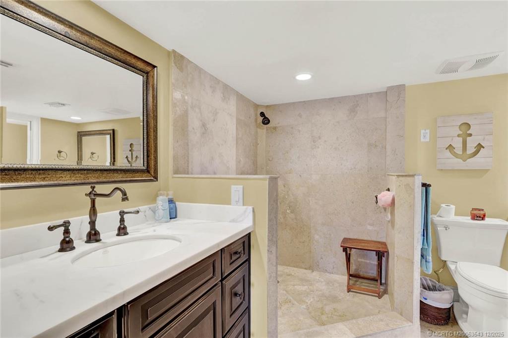 40 Northeast Plantation Road, Unit 101 Stuart, FL 34996 - Photo 18 of 37 a bathroom with a sink a toilet a mirror and vanity