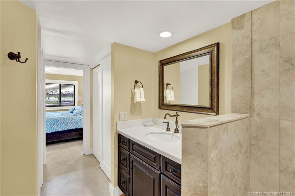 40 Northeast Plantation Road, Unit 101 Stuart, FL 34996 - Photo 20 of 37 a en suite bathroom with a granite countertop sink and a mirror