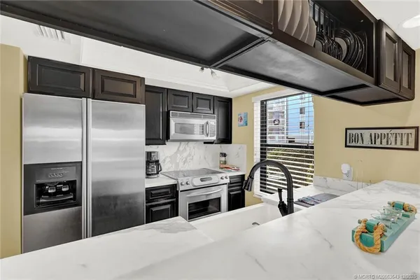 a kitchen with stainless steel appliances kitchen island granite countertop a refrigerator a stove and a sink with wooden floor