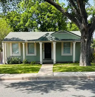 a front view of a house with a garden and trees