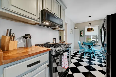 a kitchen with stainless steel appliances granite countertop a stove a refrigerator and a dining table with wooden floor