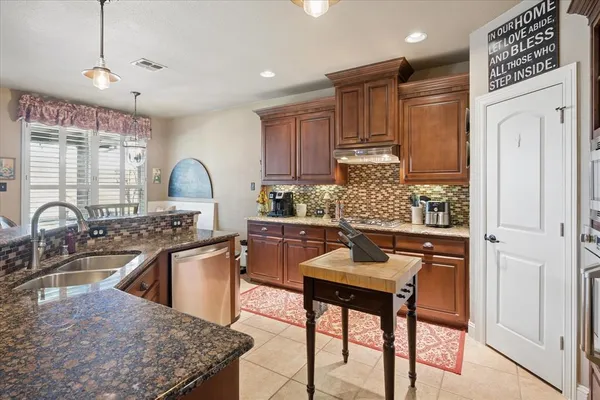 a kitchen with granite countertop a sink stainless steel appliances and cabinets